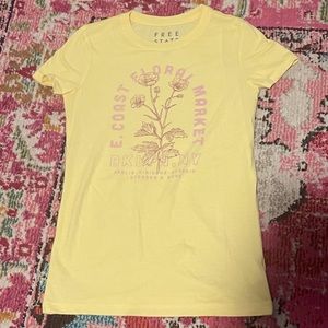 Women’s yellow “E. Coast Floral Market” graphic t-shirt with pink details